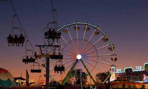 Evening sky with a lit Ferris wheel and chairlift ride at a fairground
