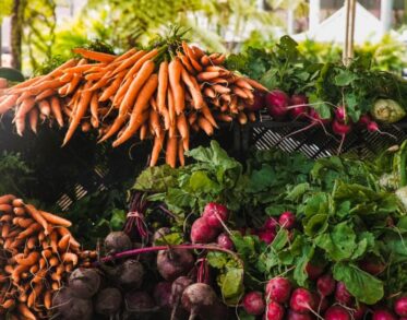 Fresh vegetables at a market with bunches of carrots and an assortment of radishes and fennel