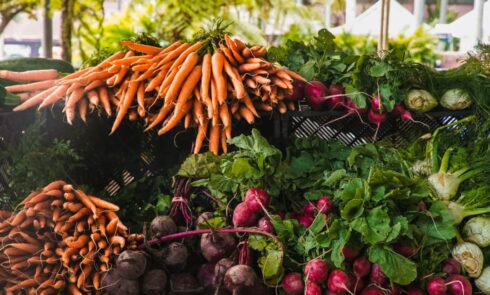 Fresh vegetables at a market with bunches of carrots and an assortment of radishes and fennel
