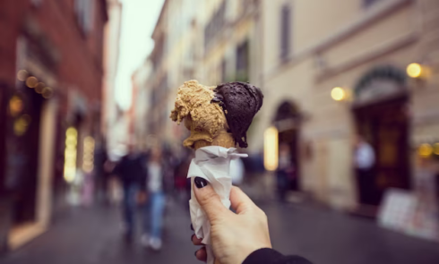 Hand holding ice cream against the background of buildings