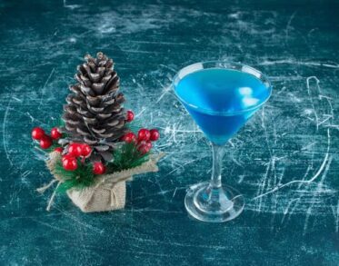 Christmas Pinecone With a Glass of Blue Cocktail